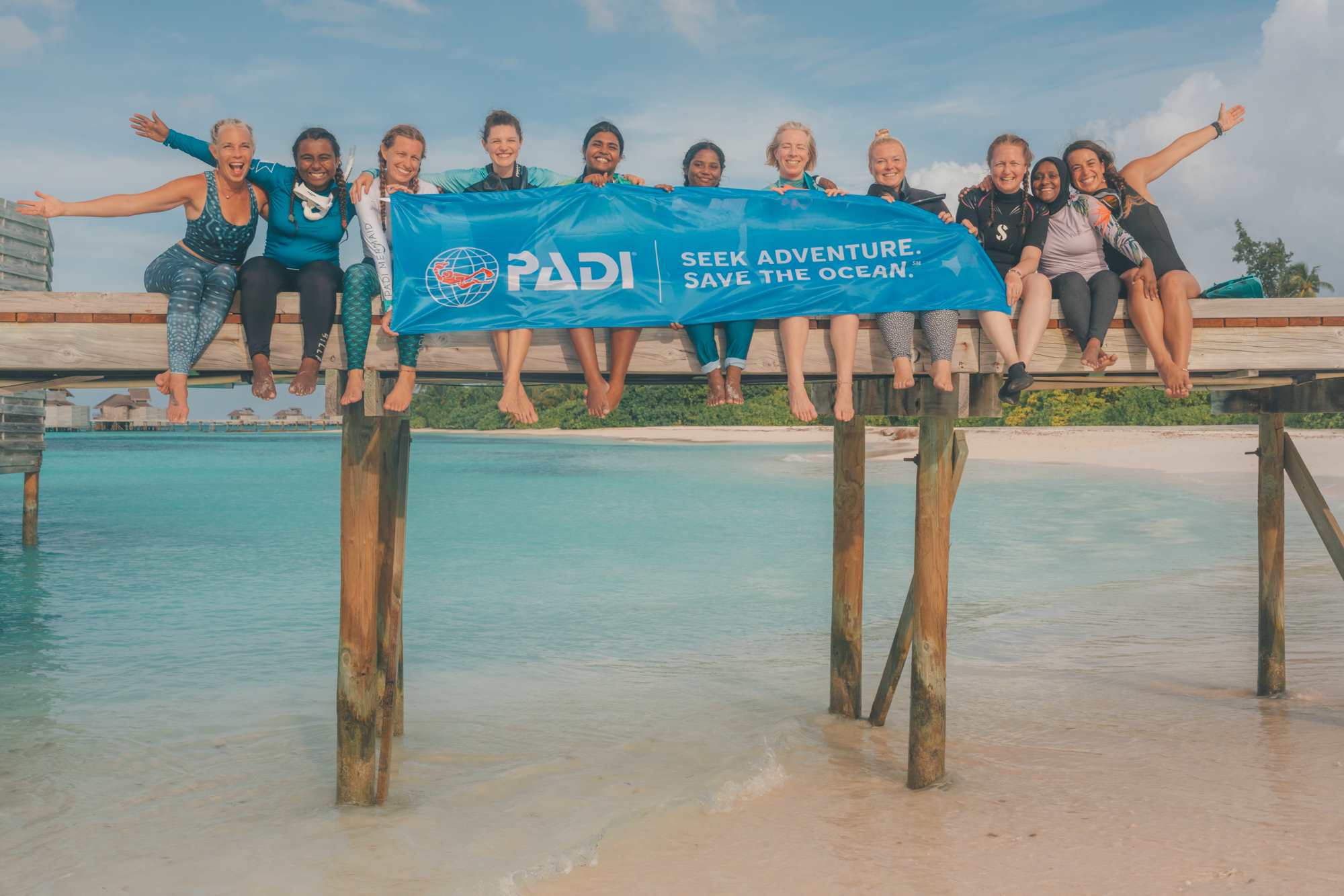 a group of women divers holding padi banner
